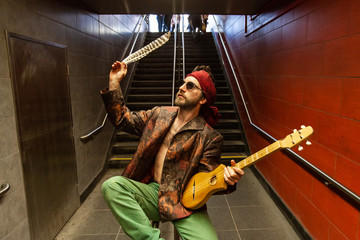 Shaman holds guitar in underground. A young Caucasian musician is seen pondering the symbolism of...