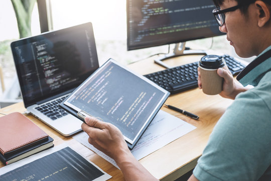 Young Professional programmer working at developing programming and website working in a software develop company office, writing codes and typing data code, Programming with HTML, PHP and javascript
