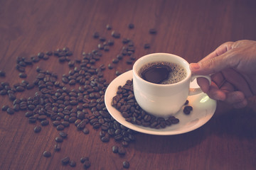 Man hand holding hot coffee cup with vintage color effected