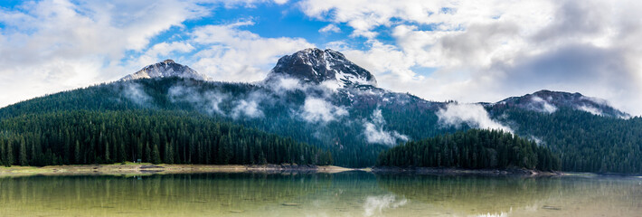 Montenegro, XXL panorama of durmitor mountains and black lake water surrounded by green coniferous...