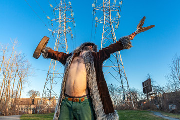 Sacred man beneath electricity towers. A shaman is viewed from the front in a trance state, his...