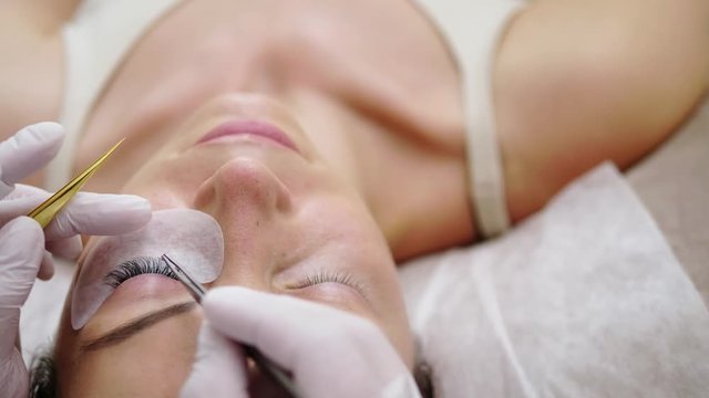 Procedure of eyelash extension in salon by cosmetician