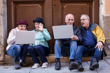 anziani seduti davanti a un portone discutono di fronte a un computer