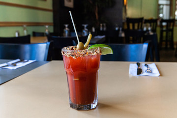 Fruity cocktail served in bistro. A freshly prepared fruit cocktail is served in a pint glass, seen close up on a restaurant table, garnished with lime and an olive, with room for copy.