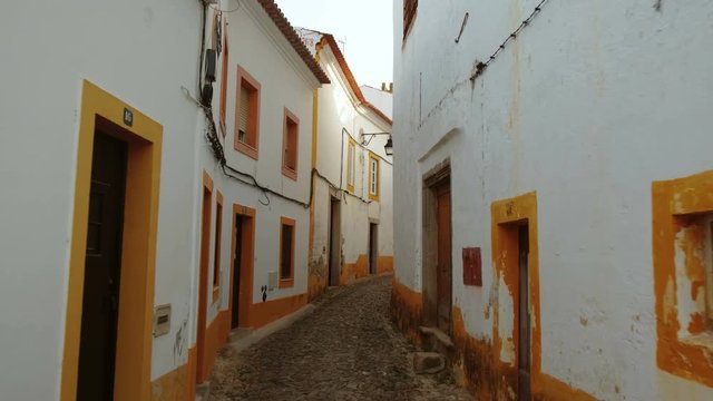 Discovering the narrow and picturesque streets of Evora, Portugal, featuring the famous whitewashed houses with yellow accents. Enclosed by medieval walls, Evora is a UNESCO World Heritage