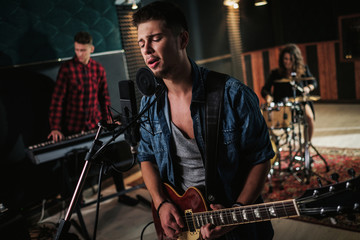 Music band having rehearsal in a studio