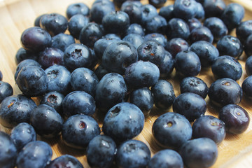 Ripe juicy blueberry on wooden plate. Food summer background