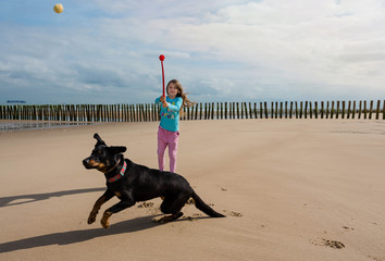 young girl playing throwing a ball at her dog