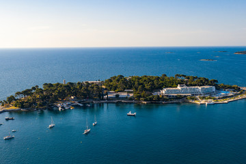 Fototapeta premium Aerial view of costal town. Aerial seaside buildings view. Aerial photo of the seashore buildings with green trees and small islands.