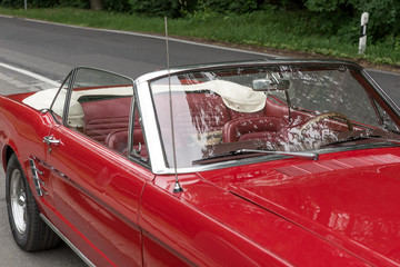 Red old cabriolet is parked at the roadside