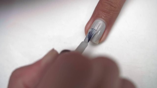 Close up of female hand applying grey polish on female fingernail