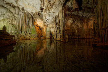 Imposing stalactites and stalacmites reflecting in a small underground lake inside the limestone cave (Tropfsteinhöhle) Grotta di Nettuno in Sardegna (Italy) © Adrian