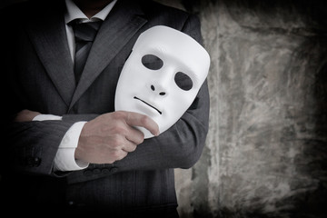 Businessman holding white mask in his hand dishonest cheating agreement.Faking and betray business...