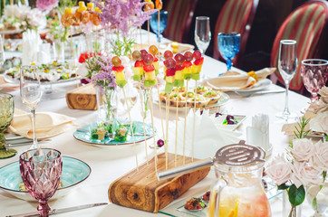 Assortment of canapes on wooden board. Banquet service with different food snacks and appetizers.. Catering food, snacks with strawberry, pineapple, fruit and berries. Party food concept.