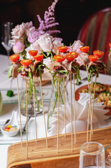 Assortment of canapes on wooden board. Balls cherry tomatoes, basil, greens on skewers, a wooden spaska. Appetizer, caprese. Catering food iIsolated on white background. Party food concept.