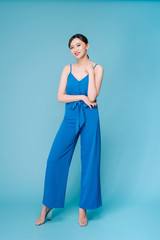 Young beautiful woman posing in new casual blue fashion costume dress with pants full body on blue...