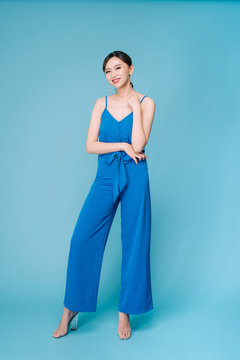 Young Beautiful Woman Posing In New Casual Blue Fashion Costume Dress With Pants Full Body On Blue Background