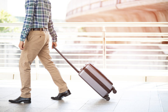 businessman walking outside public transport building with luggage in rush hour. Business traveler pulling suitcase in modern airport terminal. baggage business Trip.  Copy space. soft focus. - Powered by Adobe