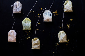 used tea bags on black wooden background