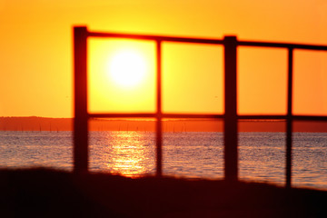 Blurred silhouette of a fence on a seashore during the sunset