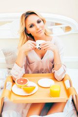 Obraz na płótnie Canvas young beauty blond woman having breakfast in bed early sunny morning, princess house interior room, healthy lifestyle concept