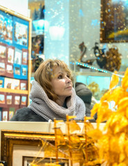 A woman chooses gifts and souvenirs for the holiday in the store. View through the window.