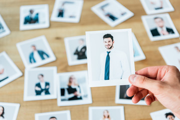 cropped view of recruiter holding photo with man in suit