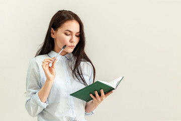 Young beautiful girl with a diary, a notebook and a pen in her hands