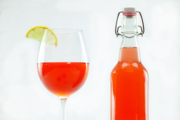 Organic & healthy homebrew mushroom tea. Refreshing red Kombucha is viewed closeup ina stemmed glass and airtight bottle, isolated against a clean white background. Versatile shot of a summer beverage
