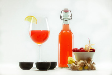 Organic & healthy homebrew mushroom tea. Thirst quenching Kombucha tea is seen against a white background with raw ingredients. Fruity alcoholic beverage in an unlabeled bottle & wineglass.
