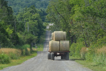 Tractor pulls wagon of Round bales of hay