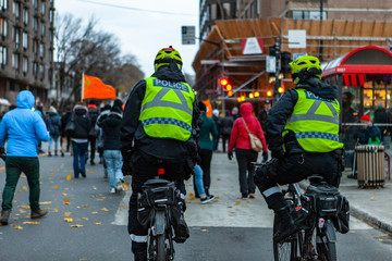 Environmental activists march in city. Two policemen are seen from the rear, riding bicycles during...