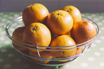 Some citrus, tangerine, mandarine oranges in a fruit bowl in a rustic kitchen. Low key and empty copy space for Editor's text.