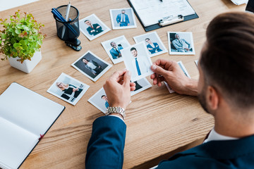 selective focus of recruiter choosing while holding photo near wooden table