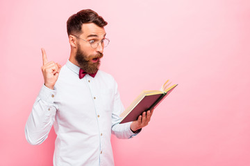 Photo of thoughtful intellectual person holding opened paper literature in hands pointing fore-finger up isolated pastel background
