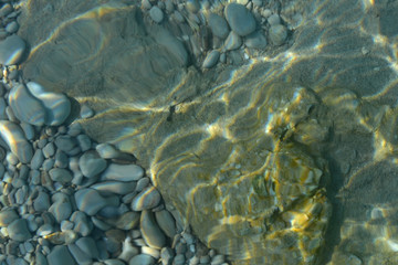 Sea stones in the sea water. Pebbles under water. The view from the top. Nautical background. Clean sea water. Transparent sea.