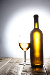 bottle of white wine and a wine glass on a wooden table with copy space for your text