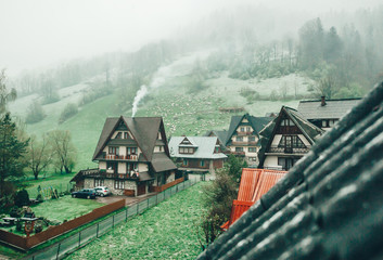 Cottage in a valley surrounded by the Tatra Mountains. A herd of grazing sheep on distance.