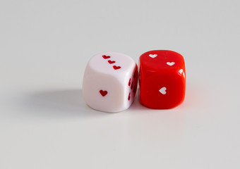 Two dice with hearts: white and red on the table. Gambling