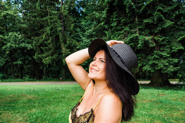 happy young woman with hat enjoying her time outside in nature near trees