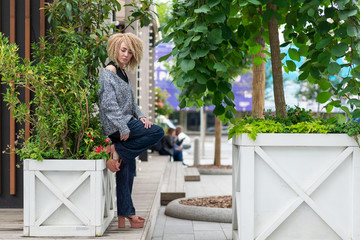 portrait girl with afro hair in knitted sweater and loose jeans thick greenery urban environment....