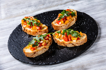 Bruschettas on black stone plate on wooden background