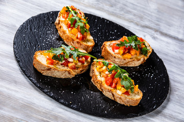 Bruschettas on black stone plate on wooden background