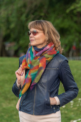 Portrait of an attractive woman wearing glasses with a backpack against a green park