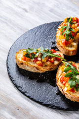 Bruschettas on black stone plate on wooden background
