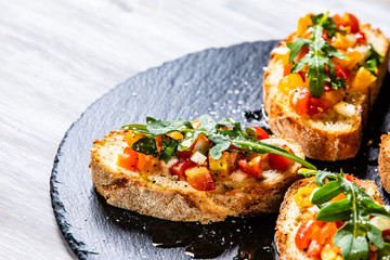 Bruschettas on black stone plate on wooden background