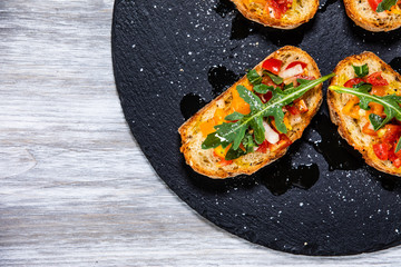Bruschettas on black stone plate on wooden background
