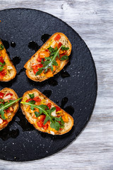 Bruschettas on black stone plate on wooden background