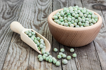Dried green peas in wooden bowl on wooden background with ladle. Peas in a bowl. Natural decoration with green p