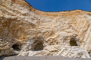 Small caves in the chalk cliffs at Freshwater Bay on the Isle of Wight, with a blue sky overhead